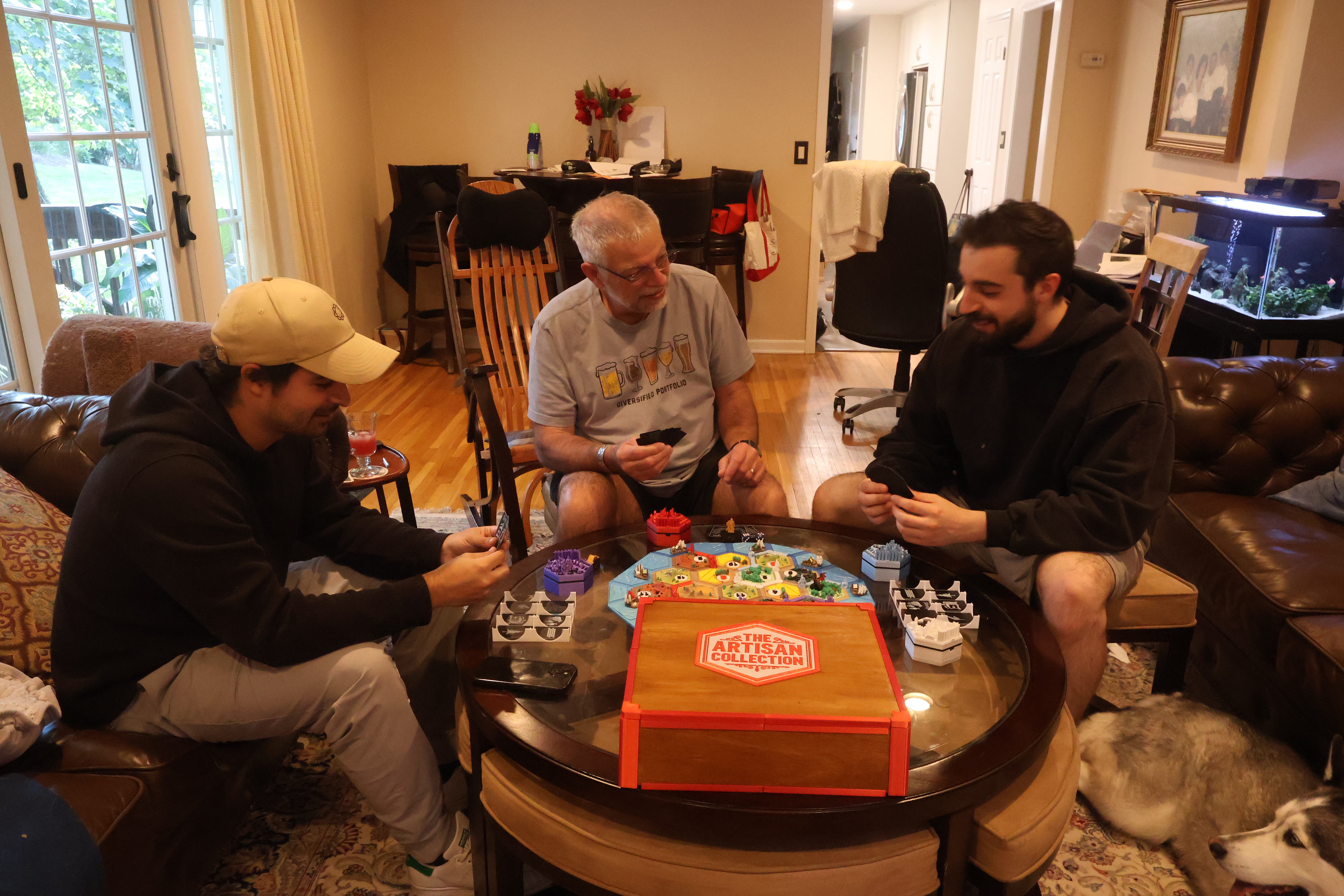 Full Catan Artisan set components laid out — magnetic hex tiles, settlements, cities, roads, custom robber, and number tokens