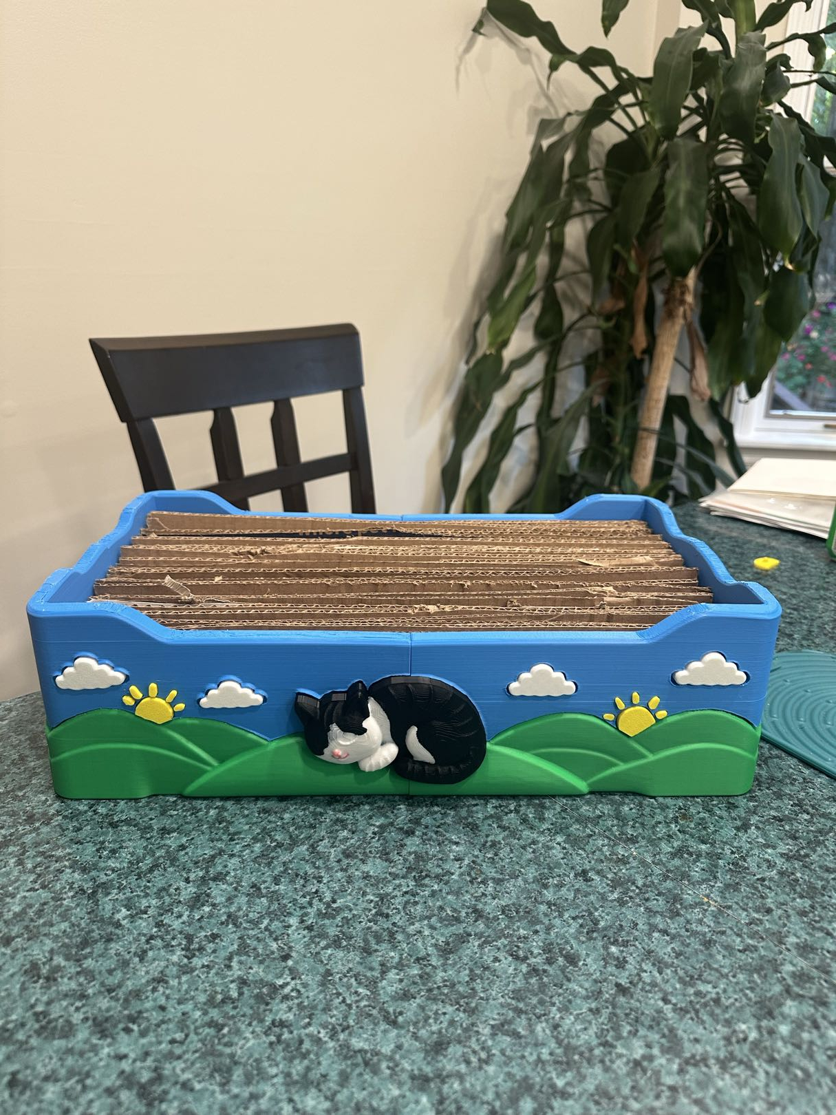Basking Paws cat scratcher, blue sky and green hills with a sleeping cat moulded into the side